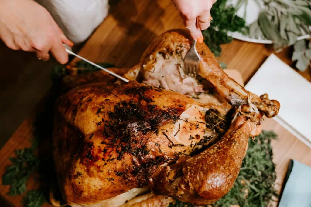 A deliciously roasted turkey being carved for Canadian Thanksgiving, with golden skin and aromatic herbs